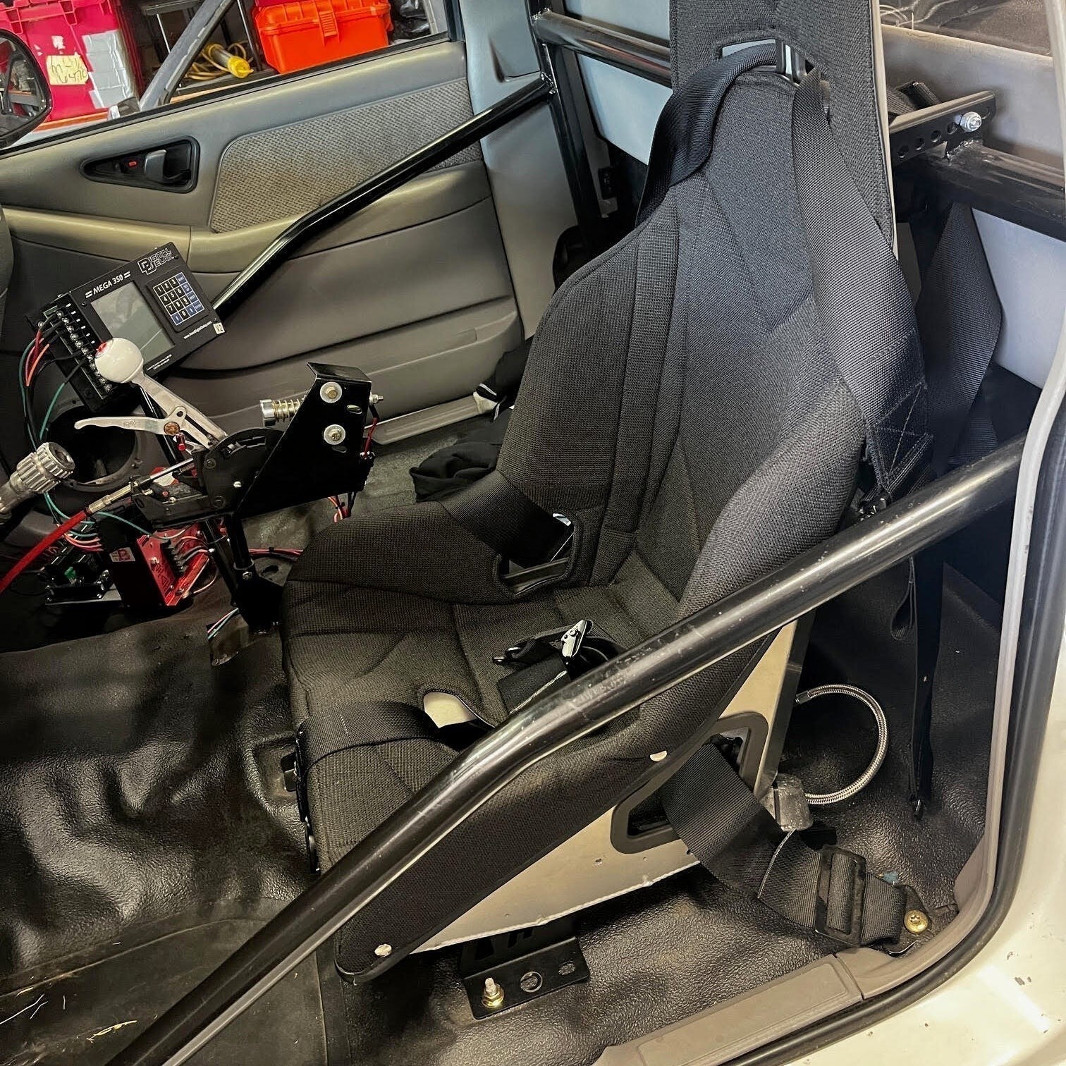 Henderson Race Shop black Kirkey racing seat installed in a GM S-Series truck with roll cage and harness