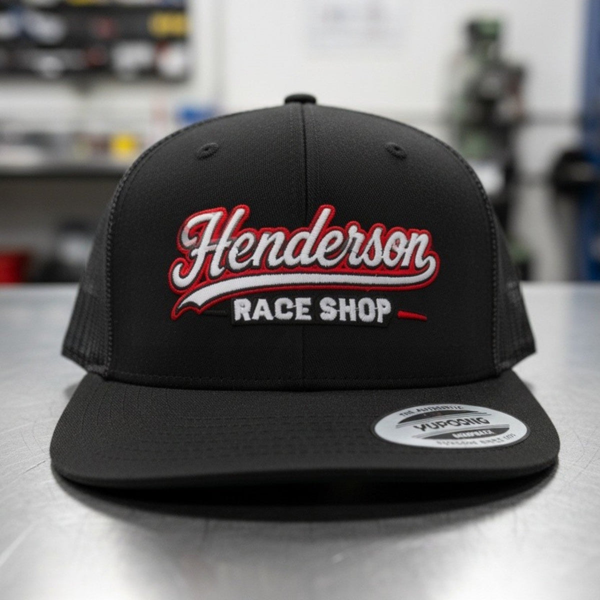 Henderson Race Shop Store black flat bill snapback hat with red and white embroidered logo on the front