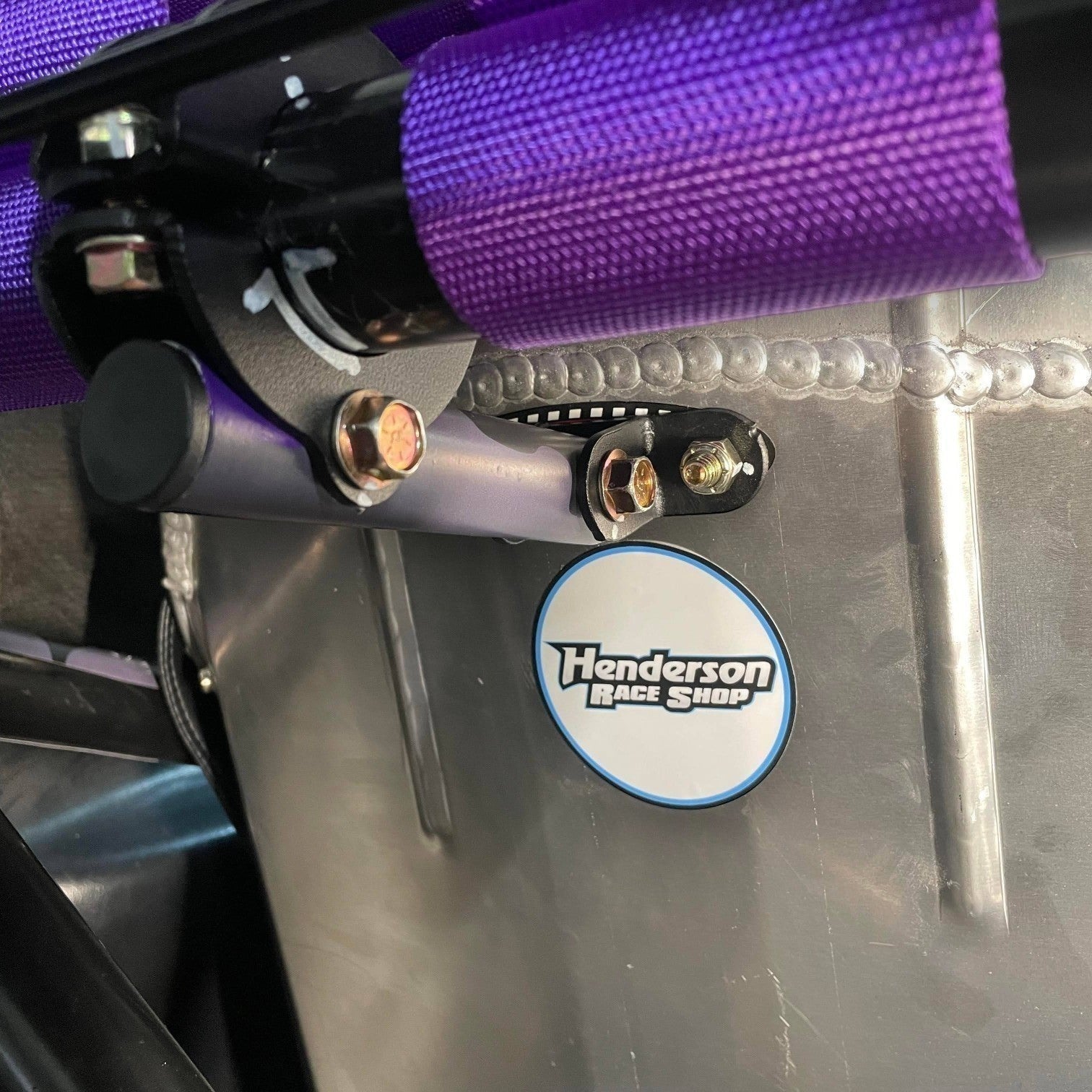 Henderson Race Shop Store bolt-on seat back brace installed on a racing seat with purple harness and metal support tube