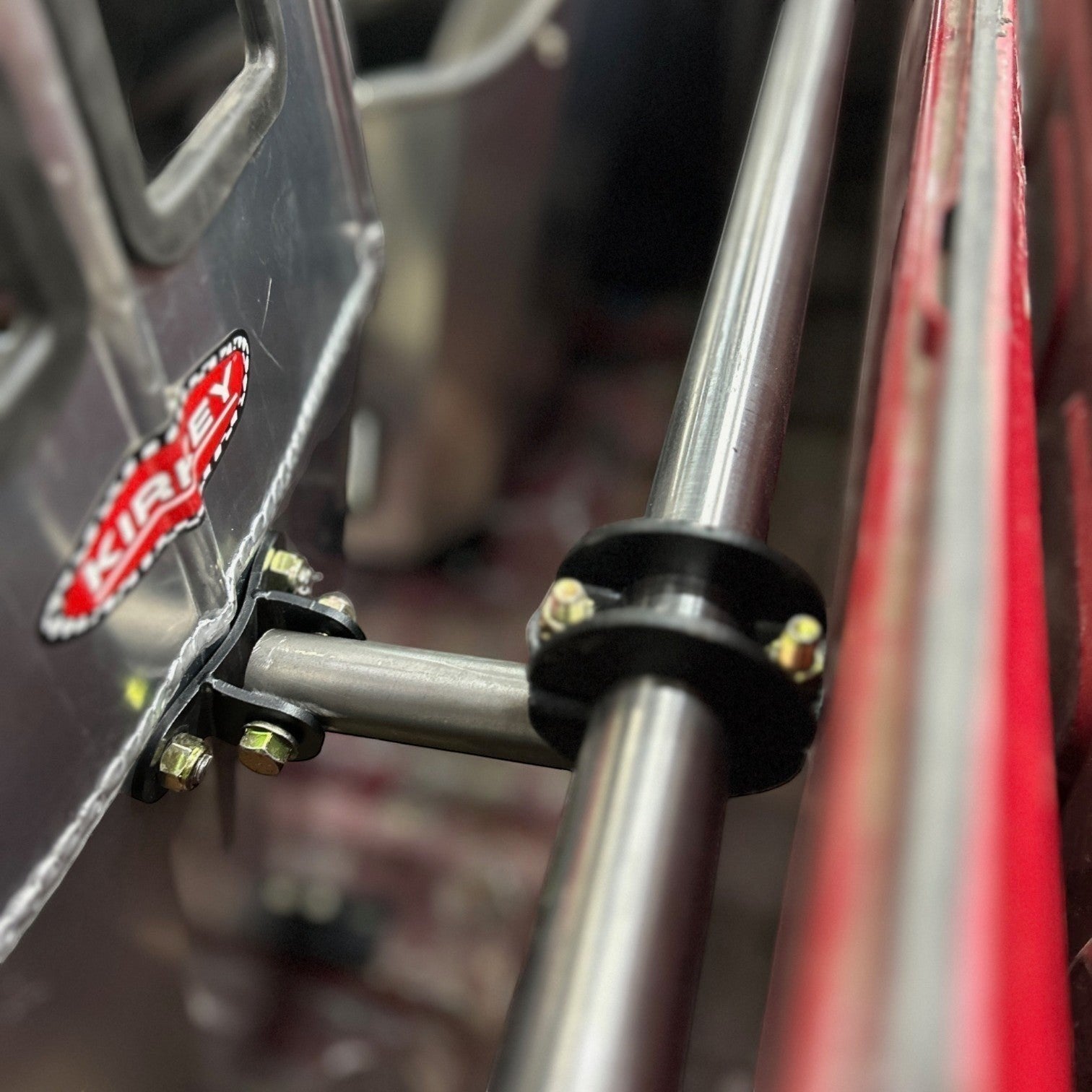 Henderson Race Shop Store bolt-on racing seat back brace attached to a harness bar with black powder-coated hardware.