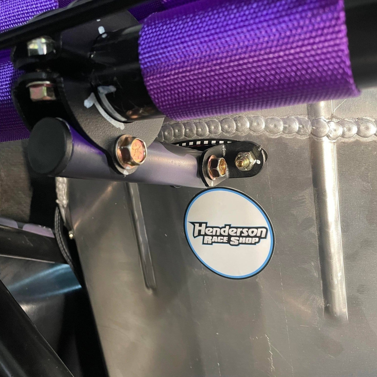 Henderson Race Shop Store bolt-on seat back brace installed on a racing seat with purple harness and metal support tube