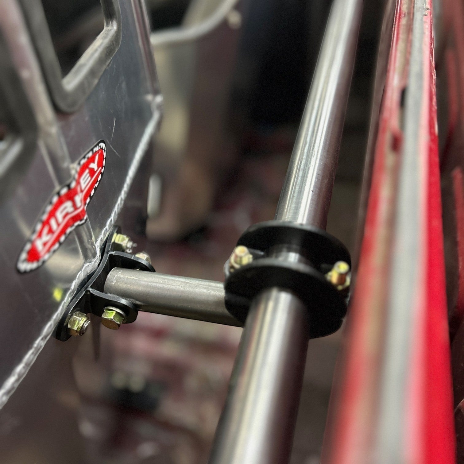 Henderson Race Shop Store bolt-on racing seat back brace attached to a harness bar with black powder-coated hardware.