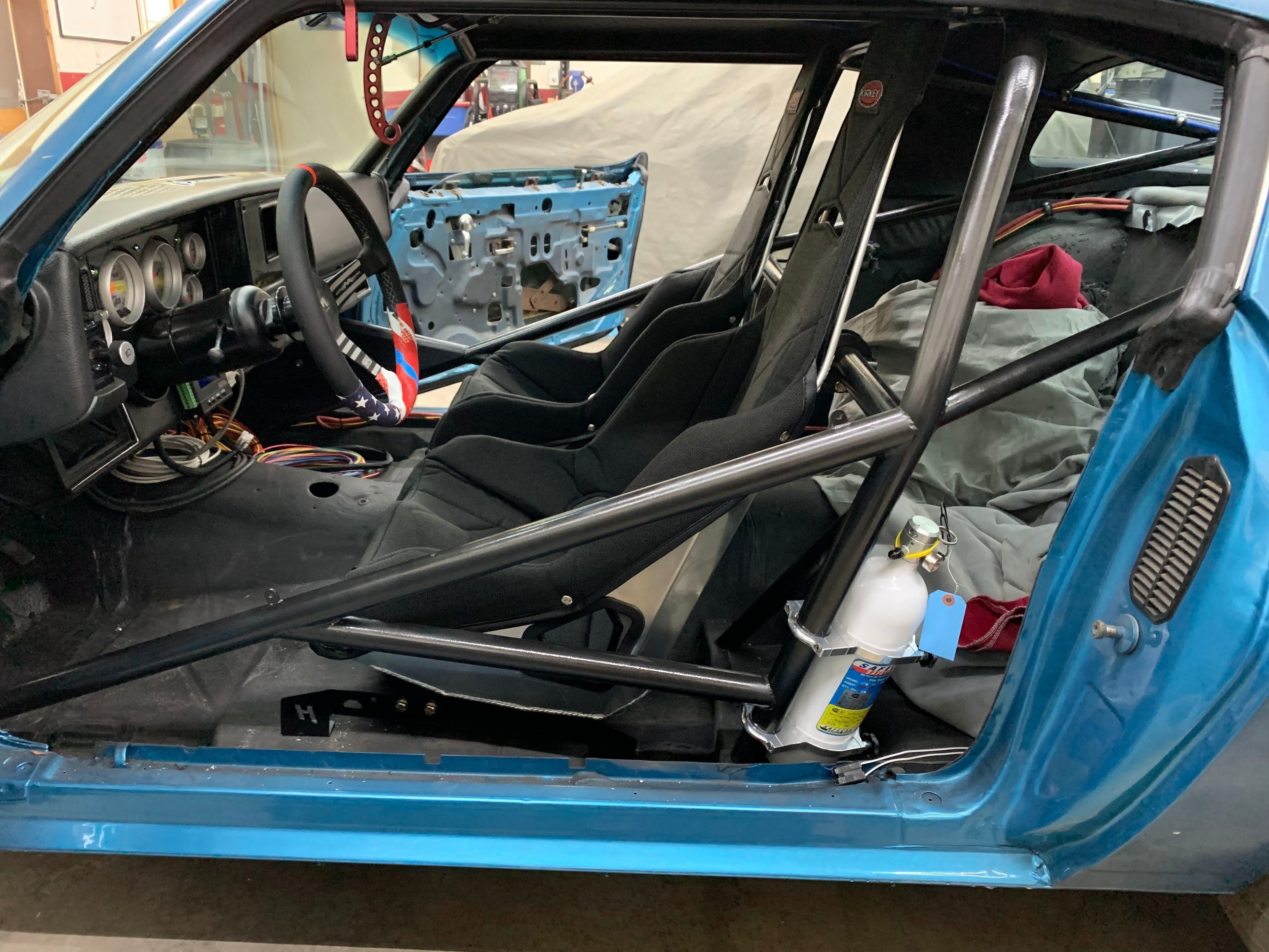 Henderson Race Shop Store seat mounts installed under a black racing seat in a blue 2nd Gen Camaro interior