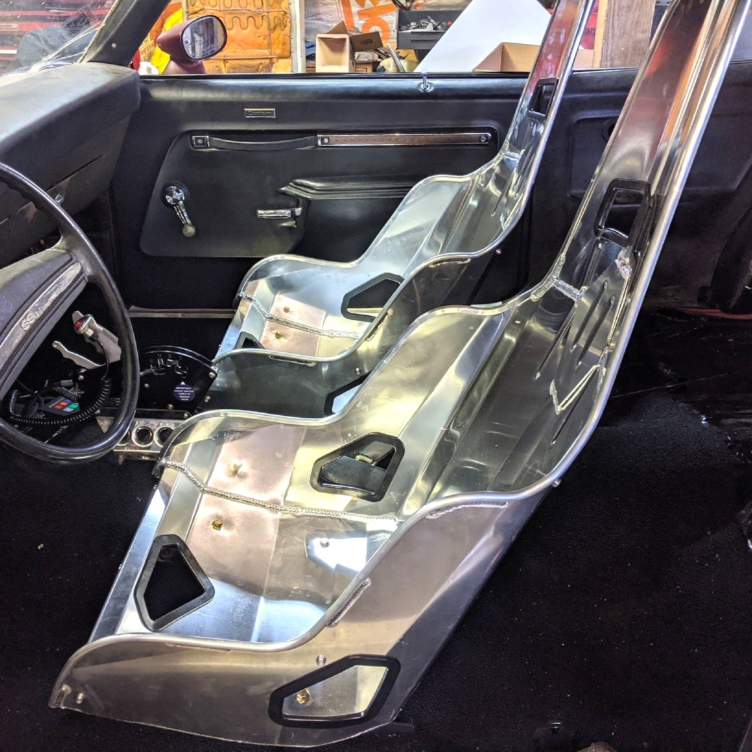 Henderson Race Shop Store seat mounts installed under aluminum racing seats in a classic Chevy II or Nova interior.