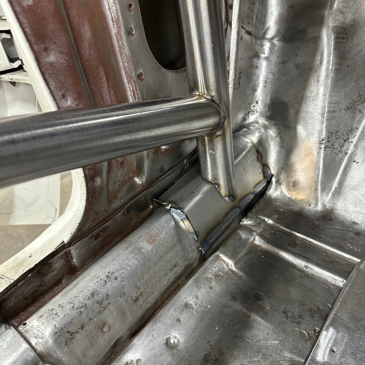 Henderson Race Shop Store 8.50 roll cage steel tubing welded to the floor and chassis of a 1971-1977 Chevy Vega