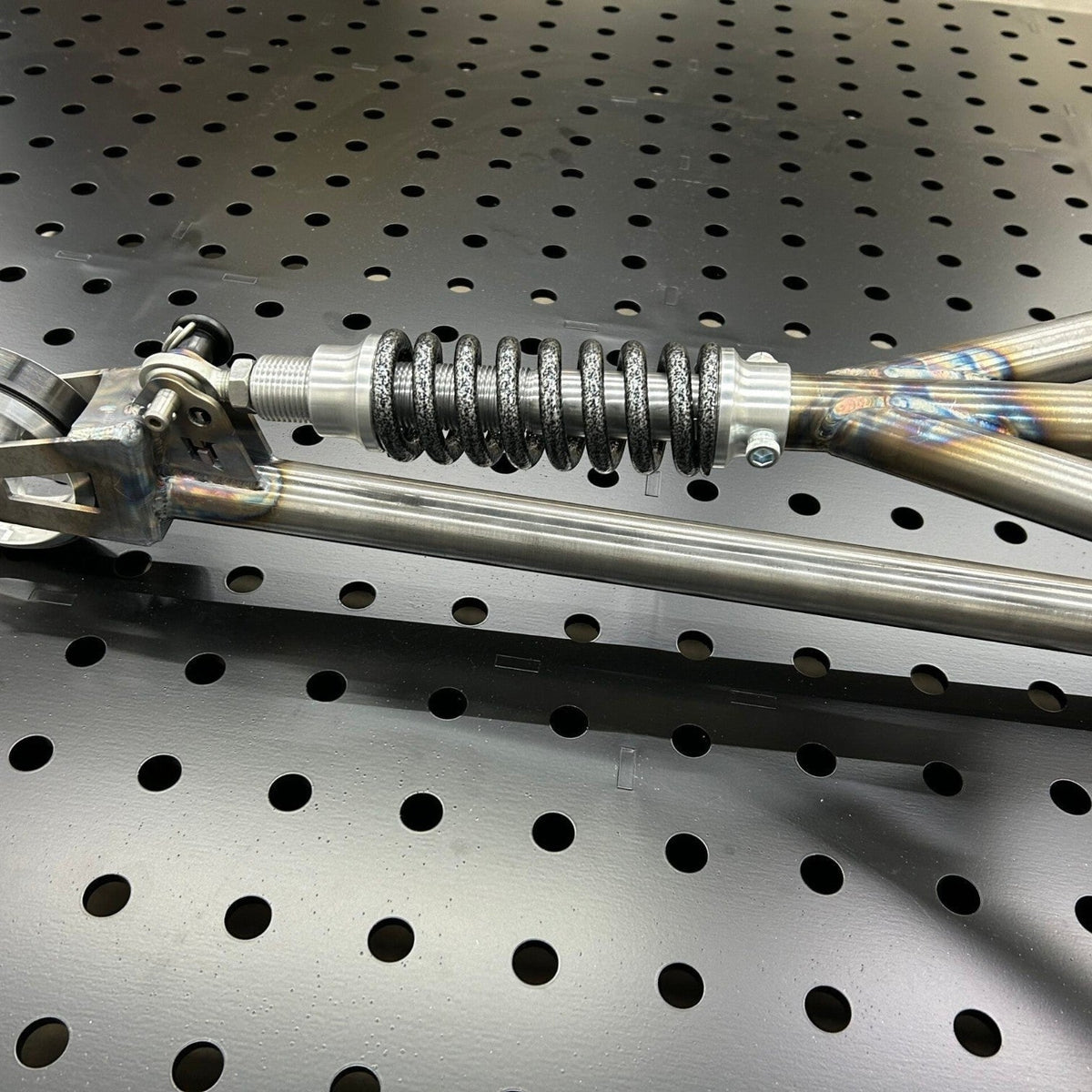 Henderson Race Shop Store single wheelie bar featuring a heavy-duty chromoly spring slider assembly on a workbench.