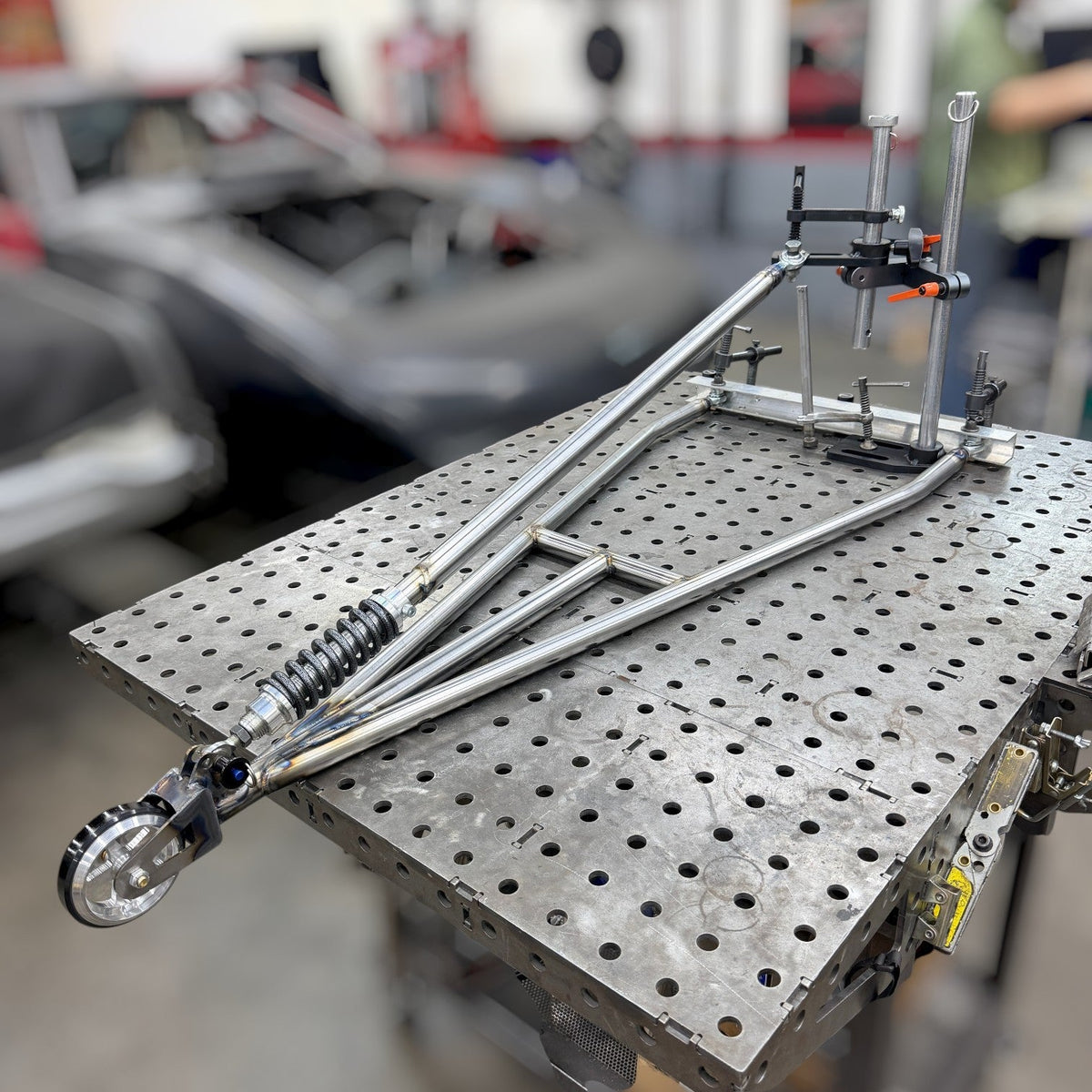 Henderson Race Shop Store heavy duty chromoly single wheelie bar with spring-loaded slider assembly on a welding table.