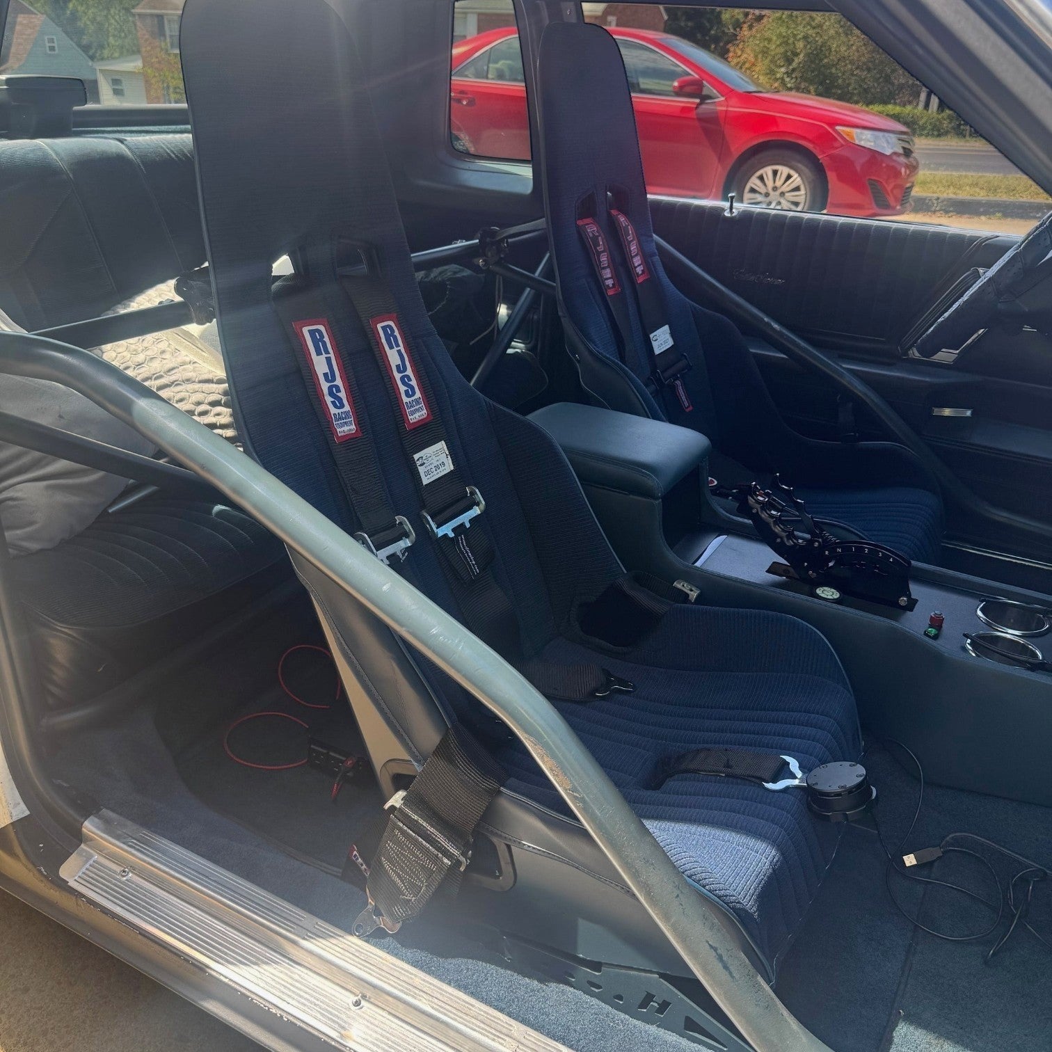 Henderson Race Shop Store seat mounts installed under blue racing seats in a GM G-Body interior with roll bar