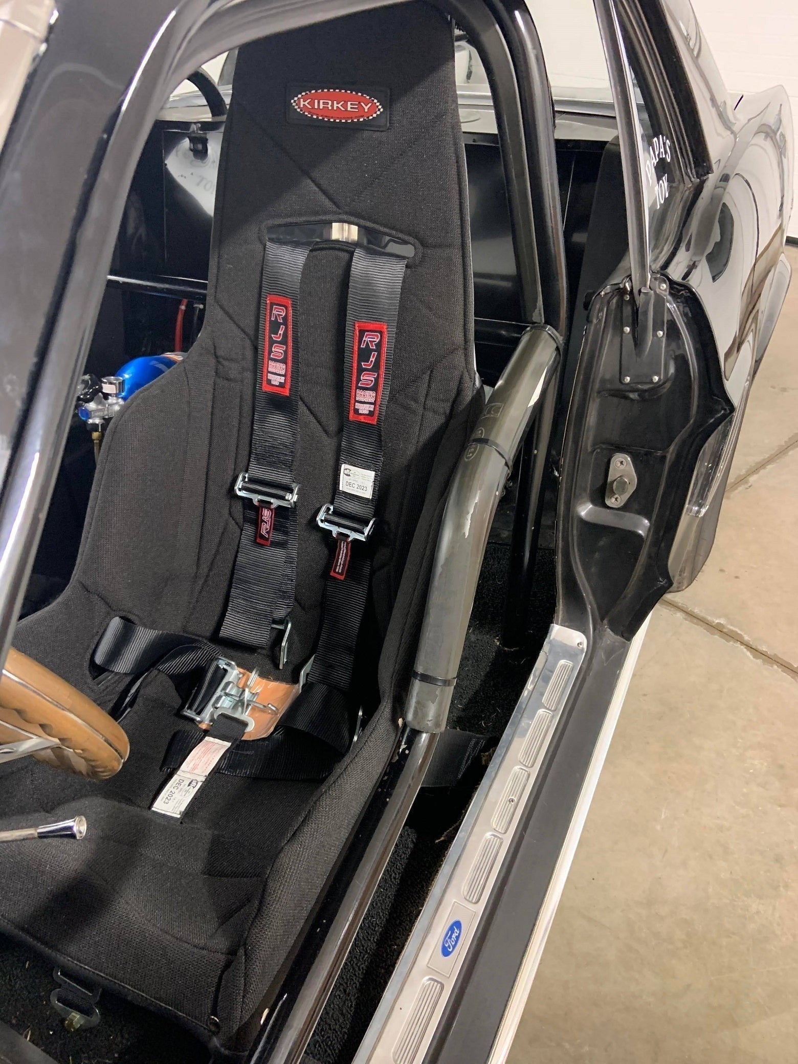 Henderson Race Shop Store Kirkey seat installed in a 1964-1970 Ford Mustang with black harness and roll cage