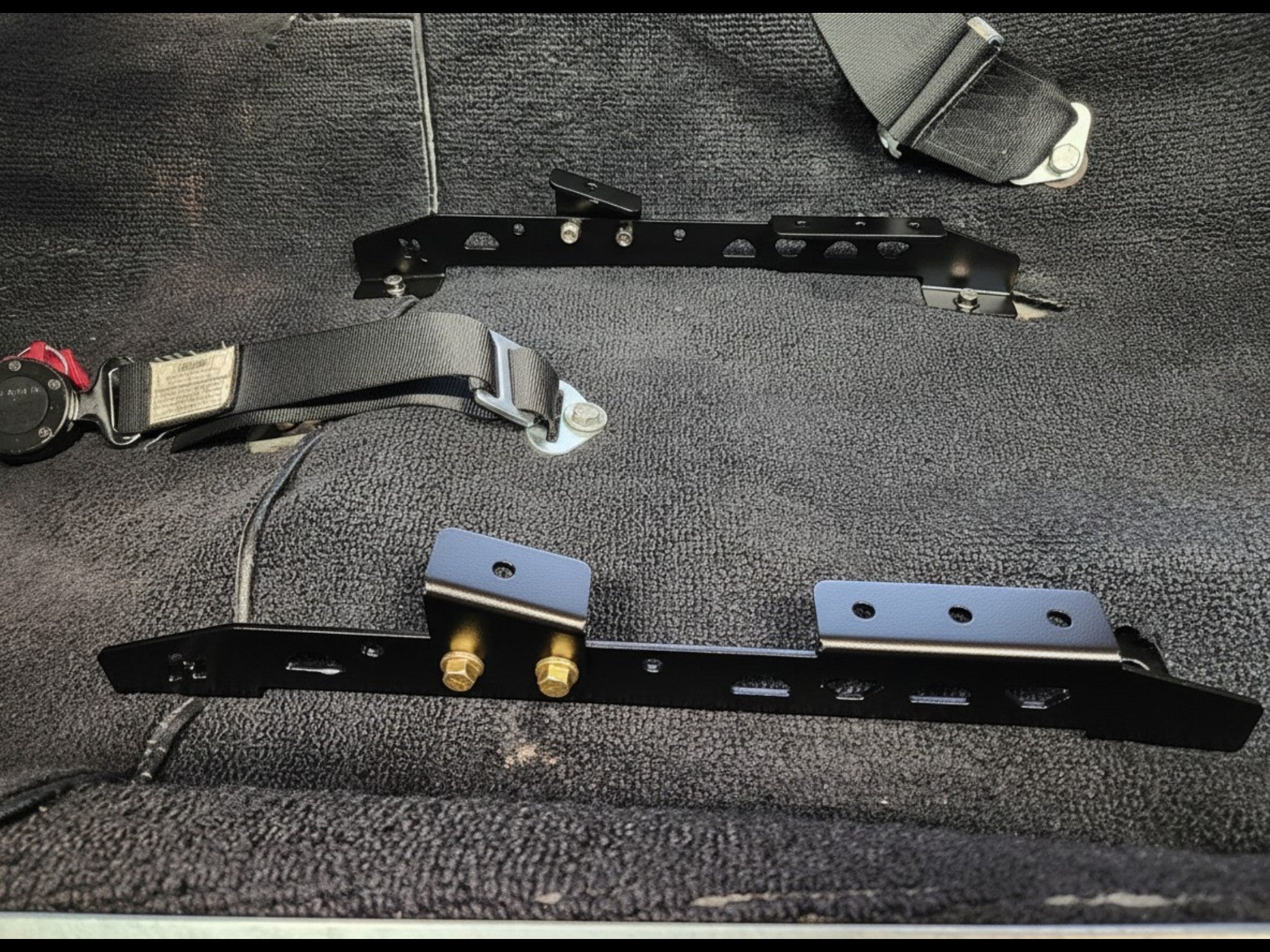 Henderson Race Shop Store black powder-coated steel seat mount brackets installed in a 2nd Gen Camaro or Firebird floor