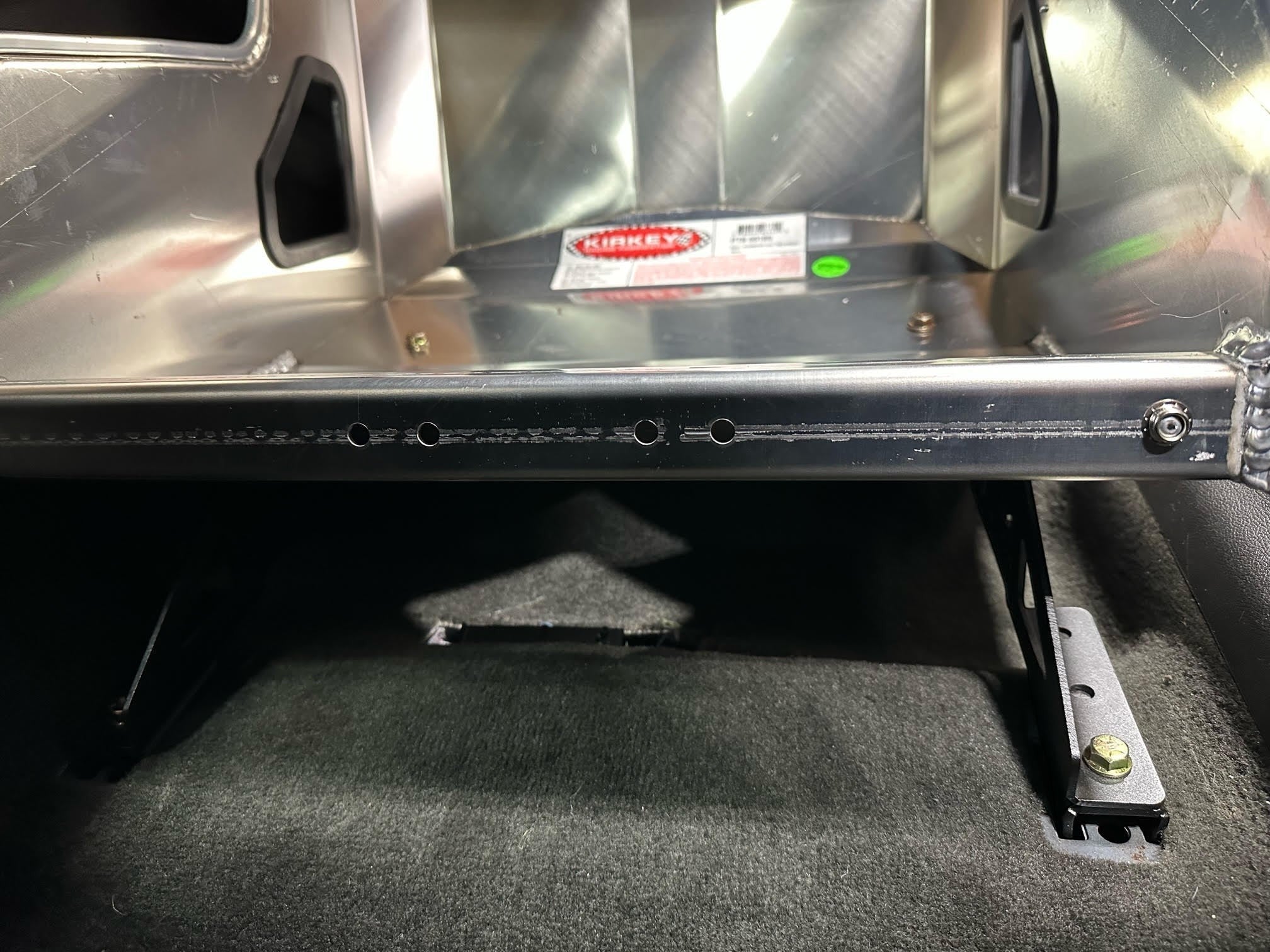Henderson Race Shop Store black powder-coated steel seat mounts installed under a Kirkey racing seat in a vehicle.