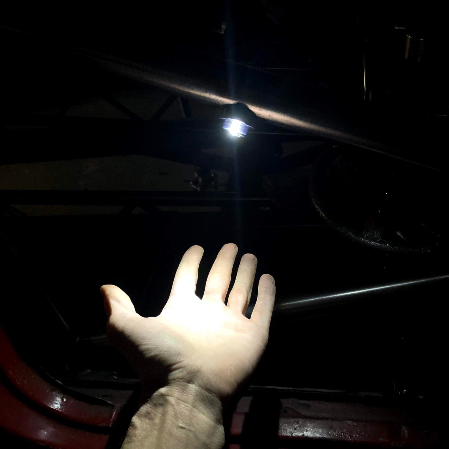 Henderson Race Shop Store magnetic LED light mounted on a roll cage, illuminating a hand in a dark race car interior.