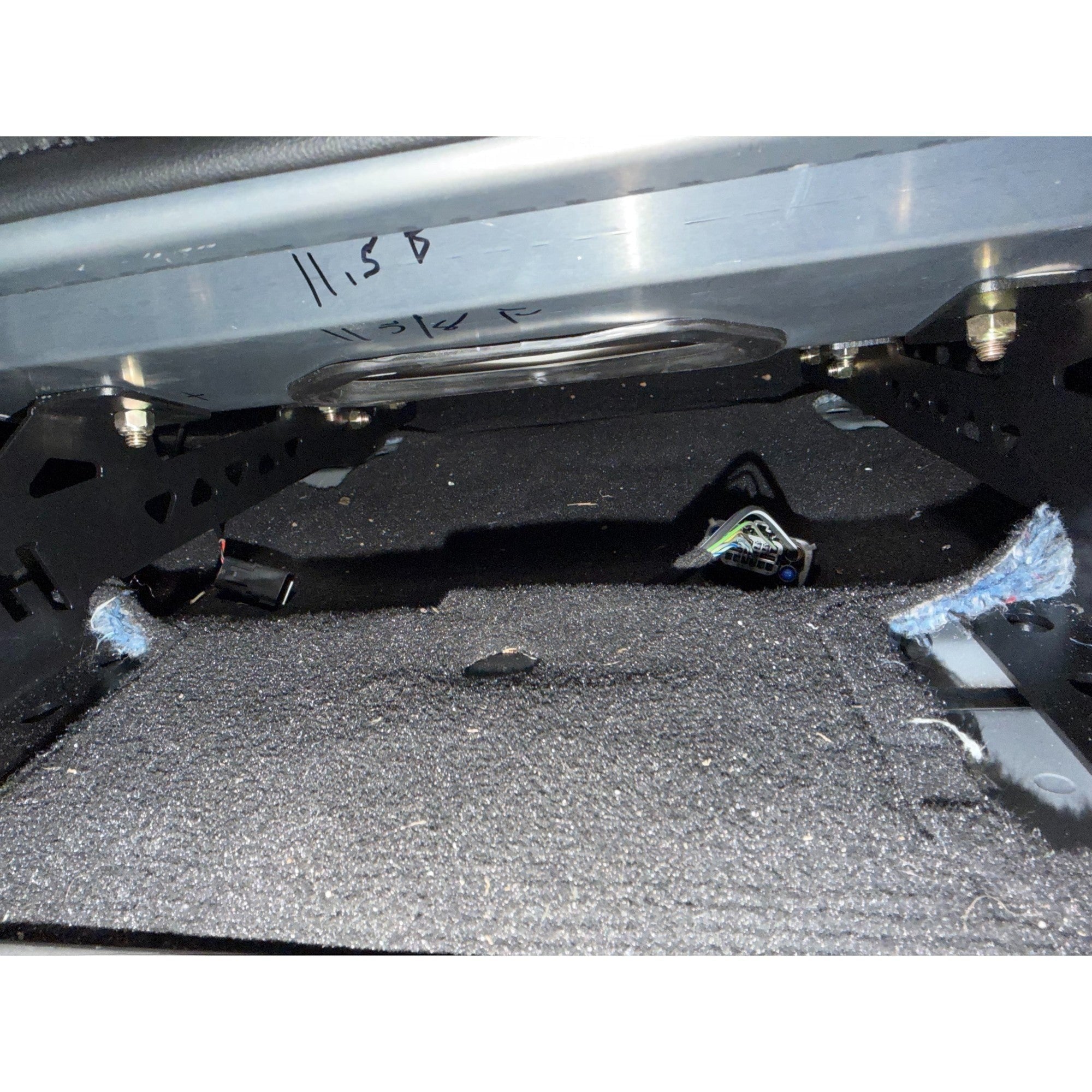 Henderson Race Shop Store black steel seat mount brackets installed in a Ford Mustang floor pan