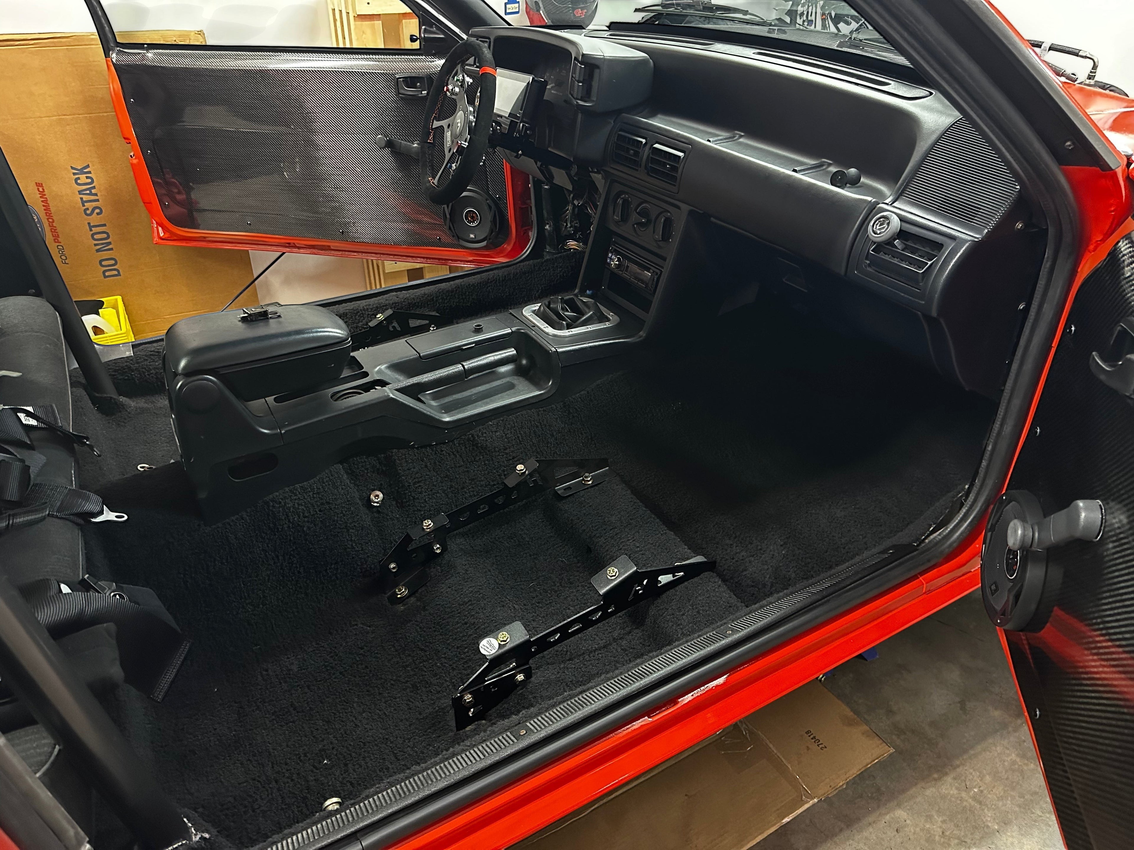 Henderson Race Shop Store black steel seat mounts installed on the carpeted floor of a red Fox body Mustang interior
