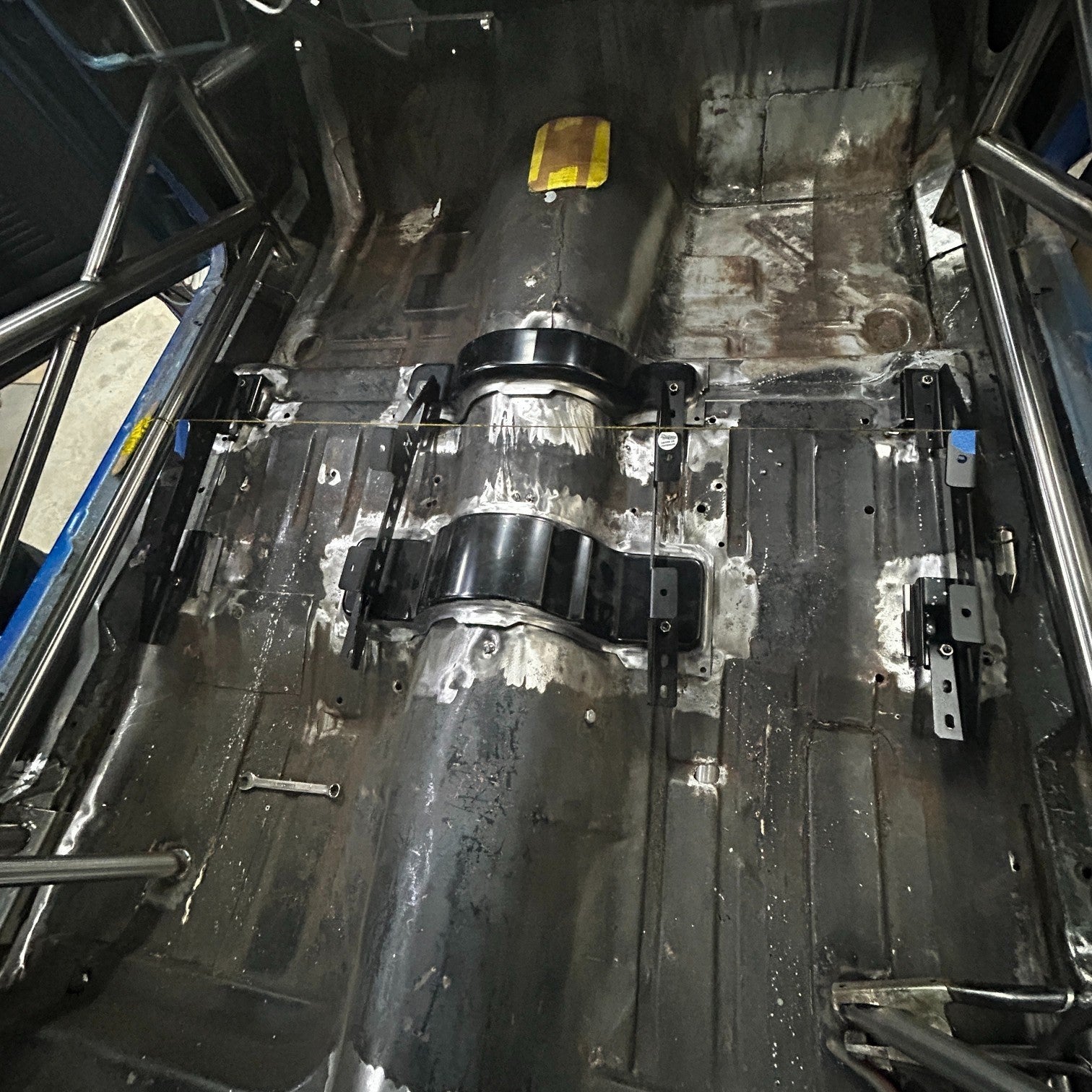 Henderson Race Shop Store seat mount brackets installed on the floor of a 1968-1974 Chevy Nova with a roll cage.