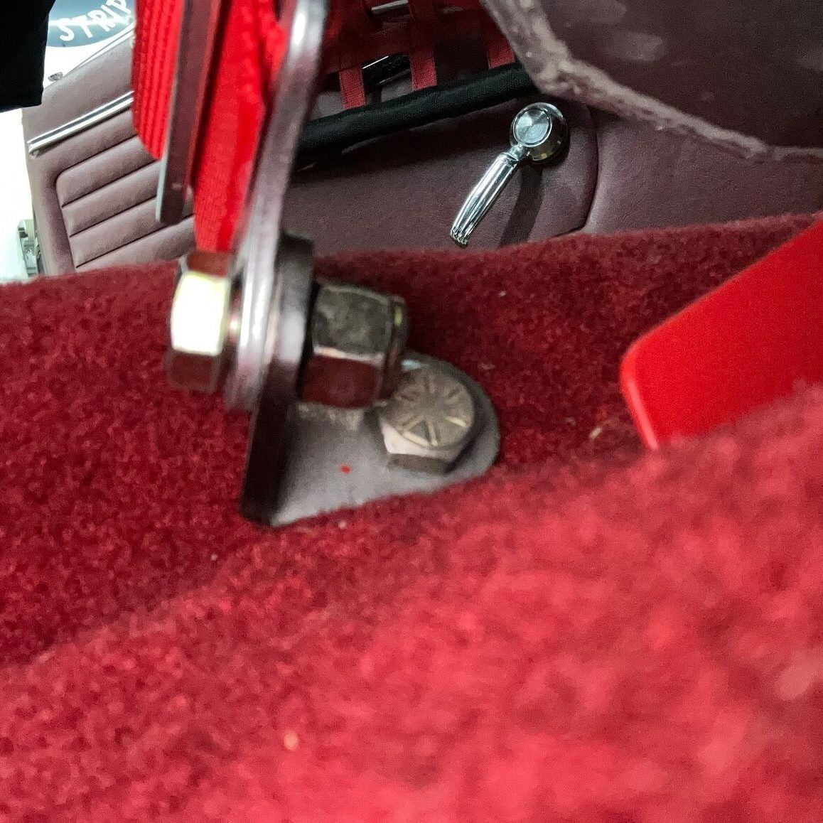 Henderson Race Shop Store 5-point racing harness floor adapter installed on a red carpeted vehicle floor