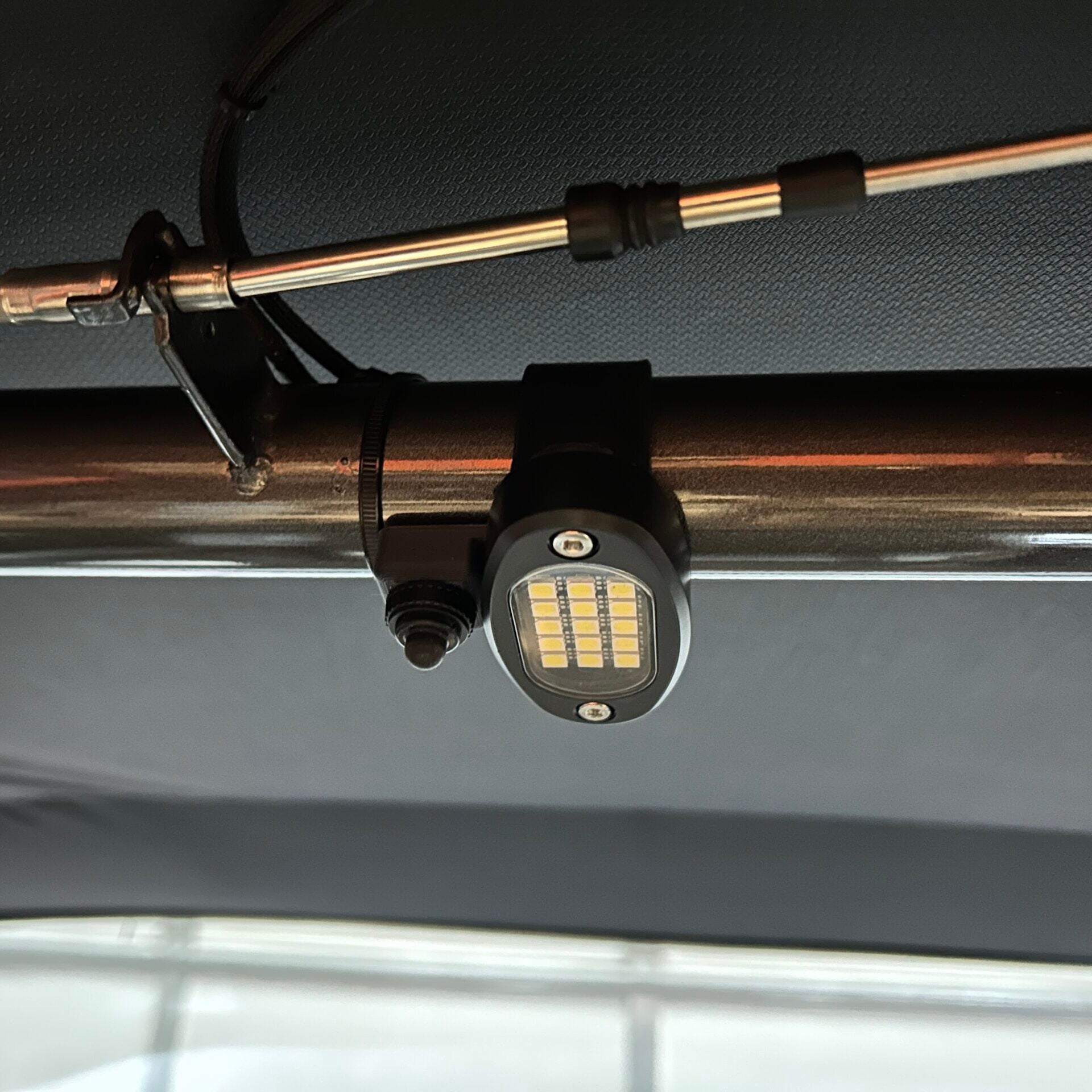 Henderson Race Shop Store LED light switch mounted on a roll cage bar next to an oval LED light fixture
