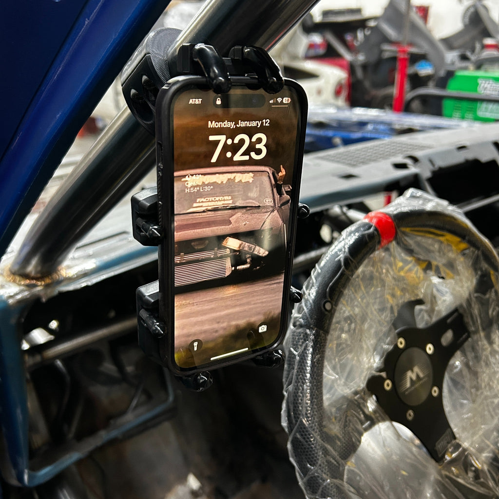 Henderson Race Shop Store roll cage phone mount securely attached to a race car roll bar with a four-sided grip.
