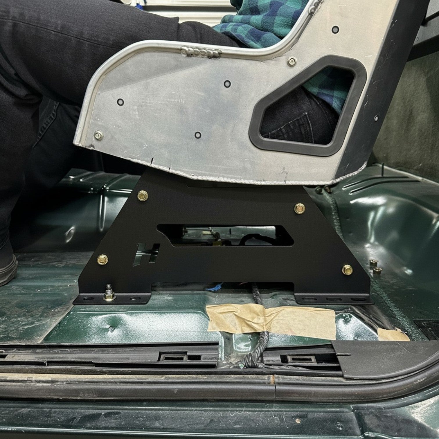 Henderson Race Shop Store seat mount bracket in black powder-coated steel installed under a Kirkey racing seat.