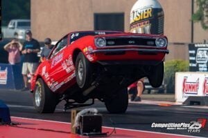 Henderson Race Shop Store single wheelie bar installed on a red drag racing car performing a wheelie on the track