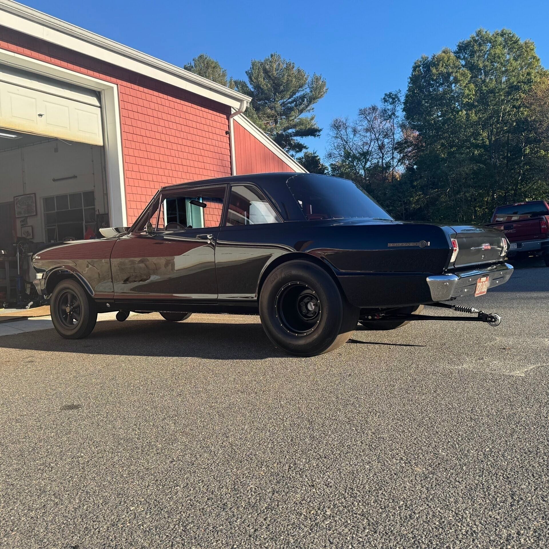 Henderson Race Shop Store single wheelie bar installed on a black classic muscle car parked outside a garage