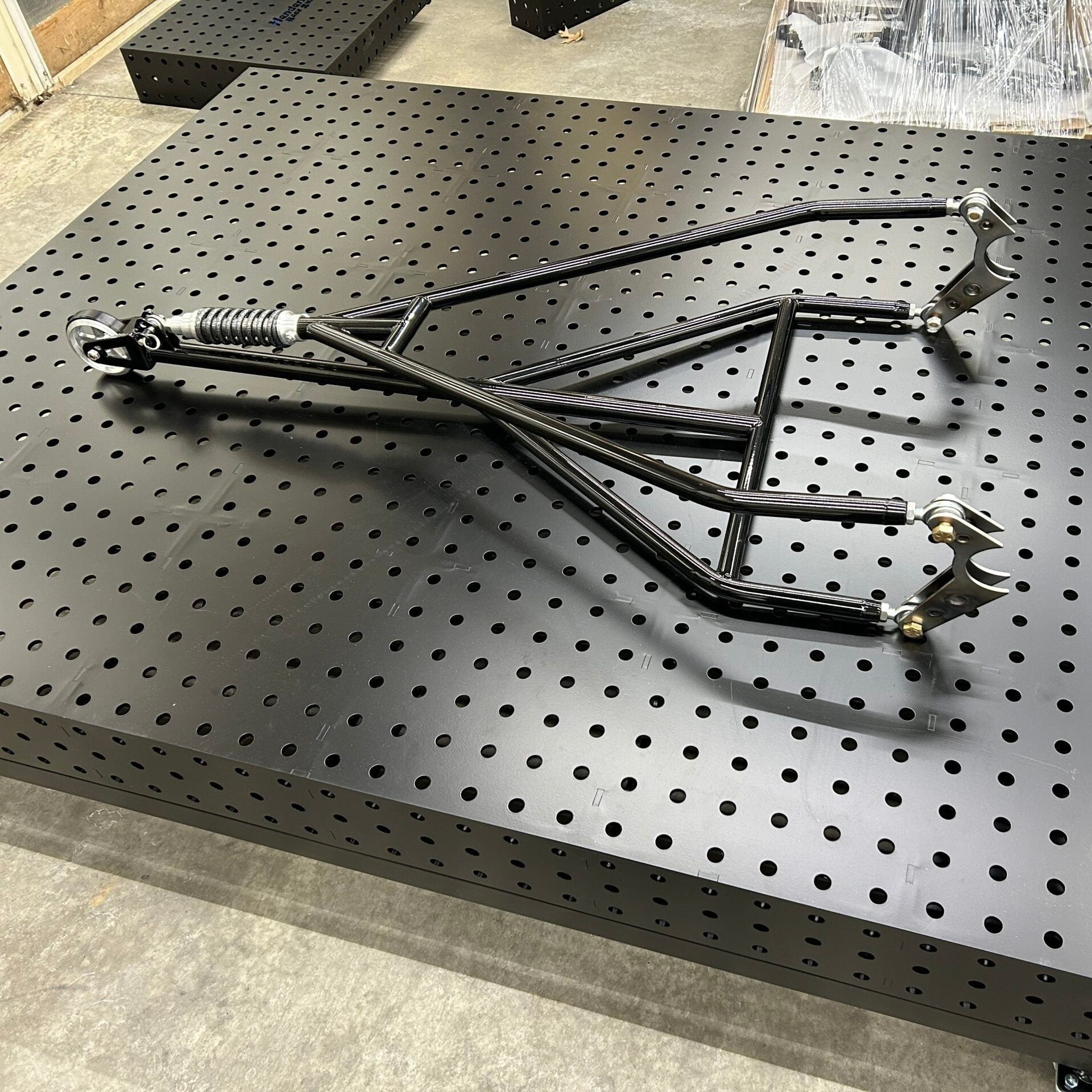 Henderson Race Shop Store single wheelie bar with heavy duty spring slider and chromoly construction on a welding table