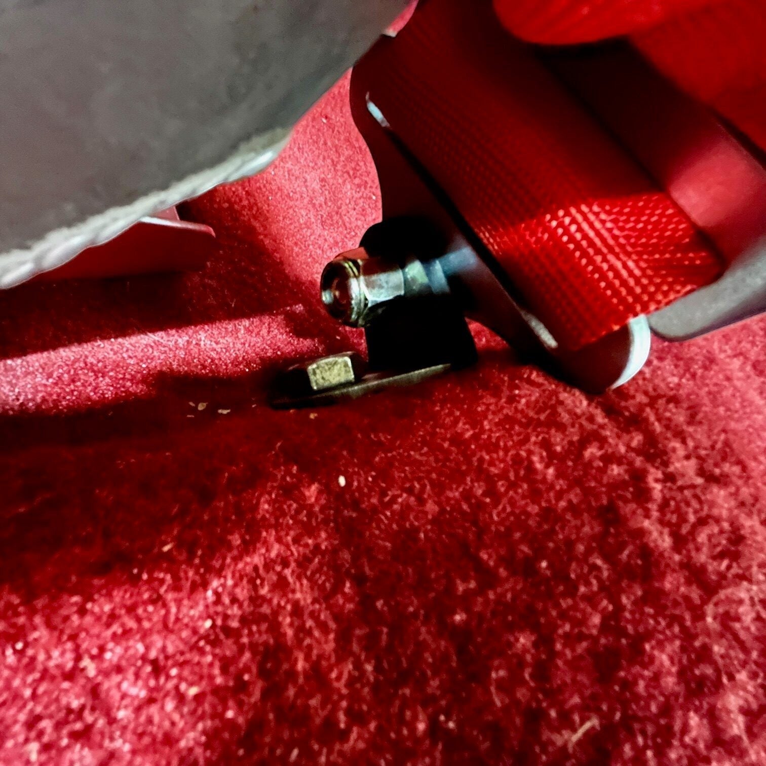 Henderson Race Shop Store black steel 5-point harness floor adapter mounted to a red carpeted vehicle floor