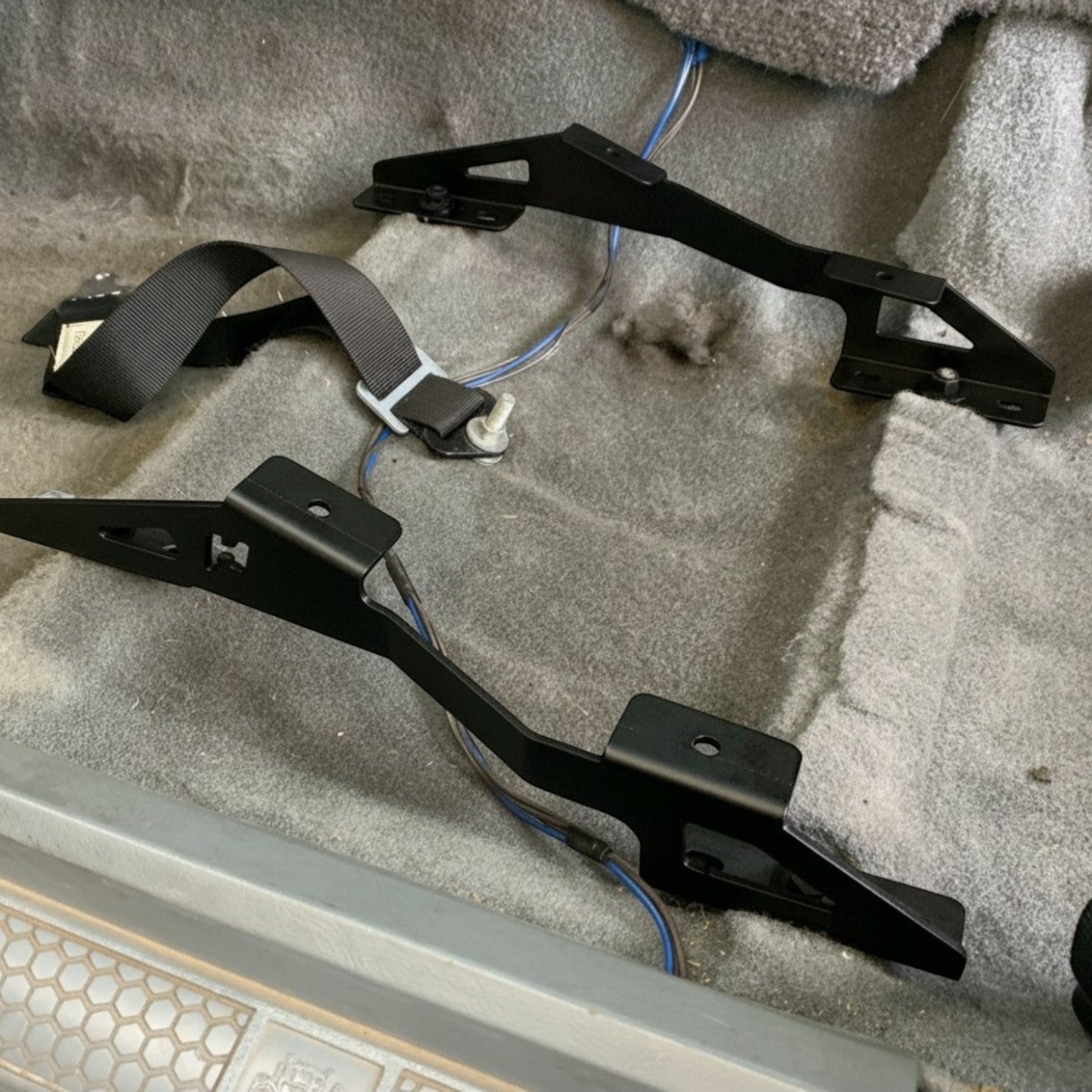 Henderson Race Shop Store black steel seat mount brackets installed on the floor of a Camaro or Firebird interior.