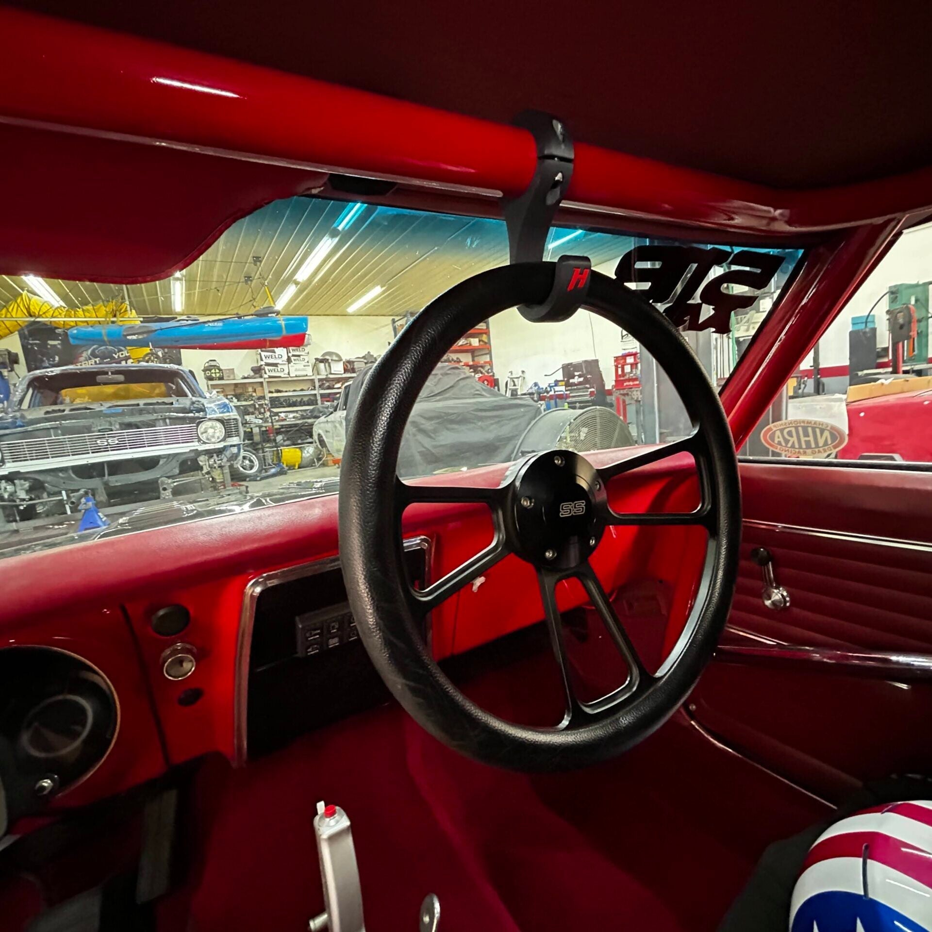 Henderson Race Shop Store black ASA hook mounted on a red roll bar holding a removable steering wheel in a race car