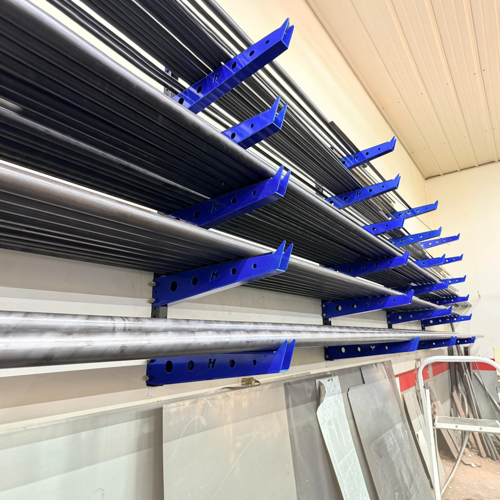 Henderson Race Shop Store wall mounted blue metal storage rack holding long steel pipes and metal sheets in a workshop