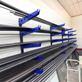 Henderson Race Shop Store wall mounted metal storage rack with blue steel arms holding long metal pipes in a workshop